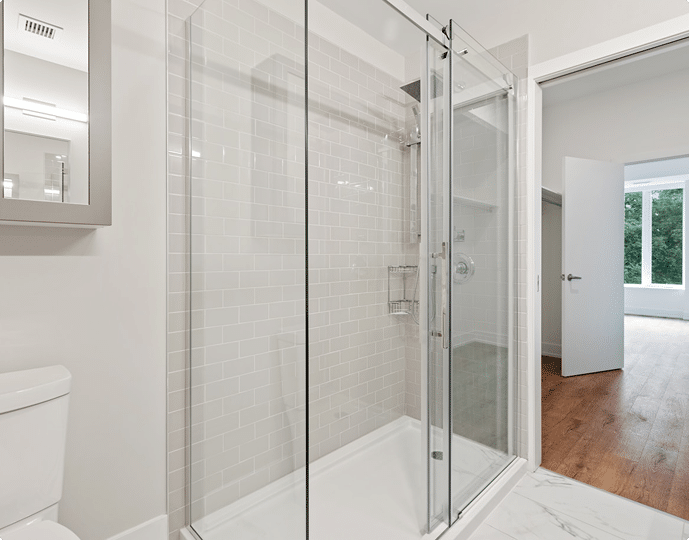 A freshly regrouted modern bathroom with a glass shower enclosure and crisp white tiles